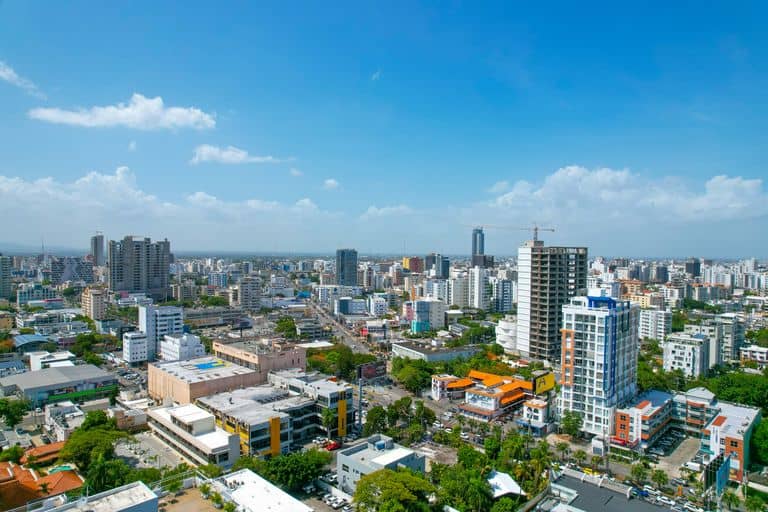 Drone aerial view of Santo Domingo's skyline showcasing urban architecture under a bright blue sky.
