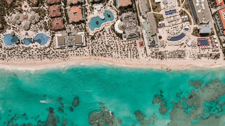 Stunning aerial view of a resort by turquoise waters and sandy beach.